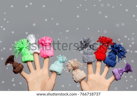Cute fingers in colorful hats as kids on winter vacation concept