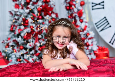 
beautiful little girl in a pink dress on a background of beautiful New Year decorations.