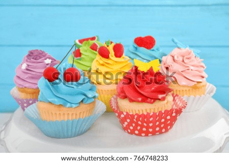 Stand with beautiful cupcakes on blurred background, closeup