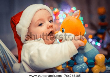 child in Santa Claus costume near the Christmas tree which glows with lights