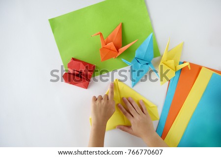 Children's hands do origami from colored paper on white background. lesson of origami Royalty-Free Stock Photo #766770607