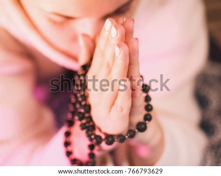 Concentrated woman praying wearing rosary beads. Namaste. Close up hands. Royalty-Free Stock Photo #766793629
