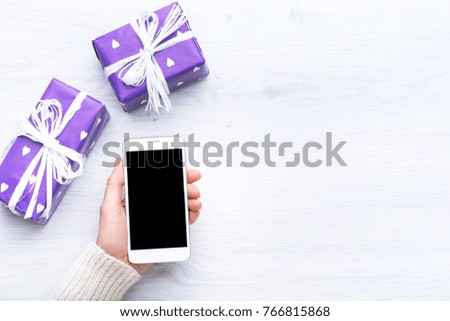 Mobile phone in hand. Portable communication device. Mobile applications. Online promotions and discounts. Holiday gifts and surprises. Present. Valentine's Day. Internet technologies