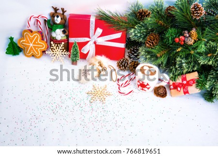 Christmas  background with Red gift box , pine with pine cones and christmas decorations, hot chocolate toy cup, toy gingerbread cooki and wooden snowflake against white snow background