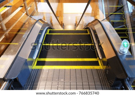 Escalator for going down direction to the ground floor with the green arrow sign on the right