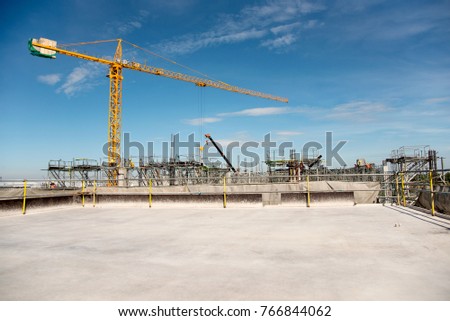 Industrial machinery and the construction crane. Cranes and skyscraper under construction, city skyline at sunset, sunrise Building for background