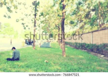 blur park scenery background image with tree grass field and a man sitting for relax.concept blur background