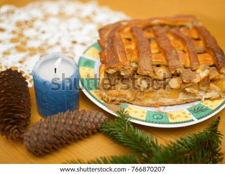 Christmas pie, pine cones and evergreen branches on a table top. Shallow depth of field