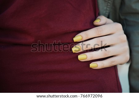 Swatch mustard yellow manicure on a background of Burgundy