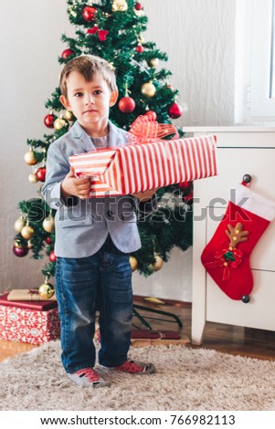 Cute little boy holding big gift package, Christmas concept