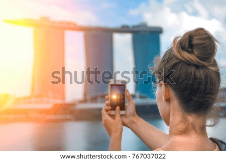 A girl is shooting the the skyline on phone at sunset in Singapore
