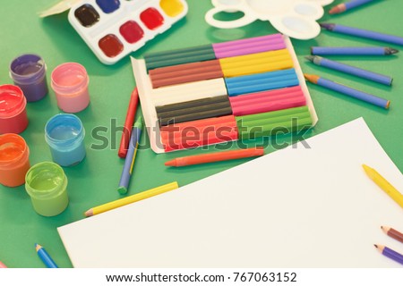 Stationery for preschoolers. Pencils, paints, an album for drawing lie on a table