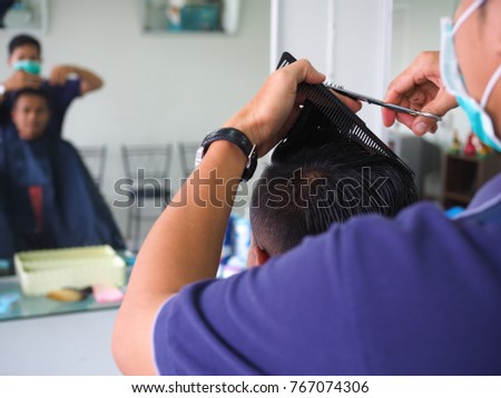 man getting haircut at barber shop. Hairdresser cutting hair of customer at salon.