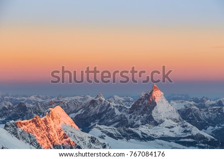 View over Matterhorn in pink sunset light as seen in summer from Margherita Hut with snowy mountains around