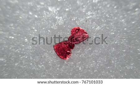 Top view close up of tiny bright red shiny hearts placed in the white glittering snow