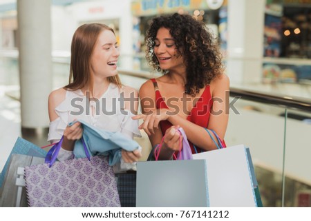 Girls are shopping at the mall. Sale in black Friday. Girls are shopping on a black Friday. The girls show each other the clothes they bought.