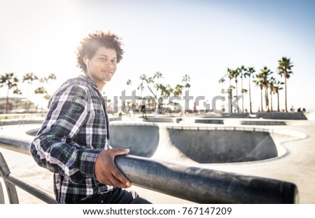 Cool skateboarder outdoors - Afroamerican guy jumping with his skate and performing a trick