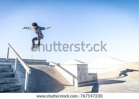 Cool skateboarder outdoors - Afroamerican guy jumping with his skate and performing a trick