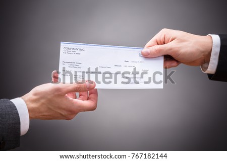 Businessperson Giving Cheque To Colleague On Grey Background Royalty-Free Stock Photo #767182144