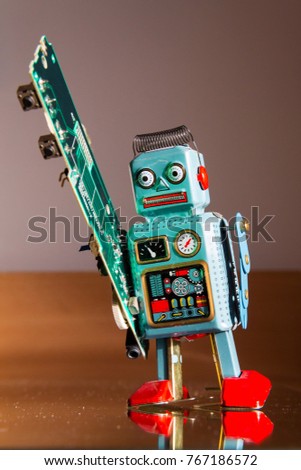 Angry vintage tin toy robot carries green computer circuit board, artificial intelligence concept