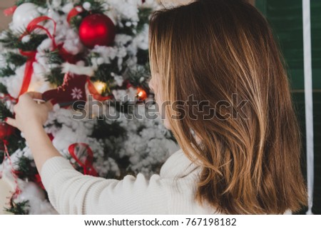 Young woman from behind decorating Christmas tree 