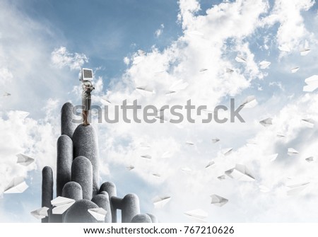 Business woman in suit with monitor instead of head keeping arms crossed while standing on the top of stone columns among flying paper planes with beautiful landscape on background. 3D rendering.