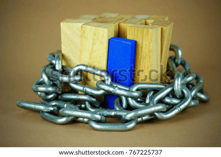 Wooden block standing and outstanding among the business trap with chain, business concept able to survive or dominant from destruction, selective focus and vignette effect.