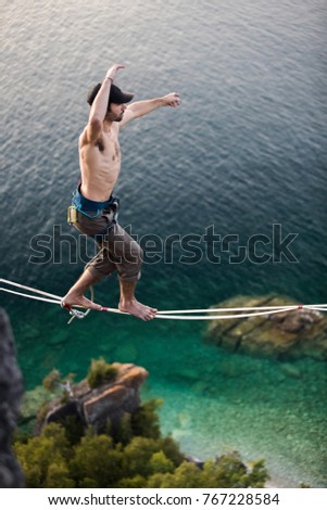 Man walking a high line slack line high above water