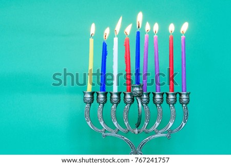 Image of jewish holiday Hanukkah on happy green background with menorah (traditional candelabra) and burning candles.