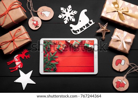 New year's background on a black desk decorated with toys, presents, Christmas tree. Bright colored background symbolizes the new year celebration. Great useful template with a tablet.