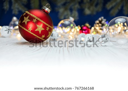 red glass christmas ball and wooden sledge toy on background with festive colorful holiday lights
