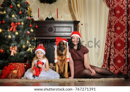 Mom, daughter and dog under the New Year tree