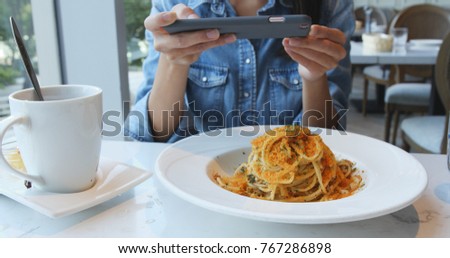 Woman taking photo on cellphone in restaurant for her dish