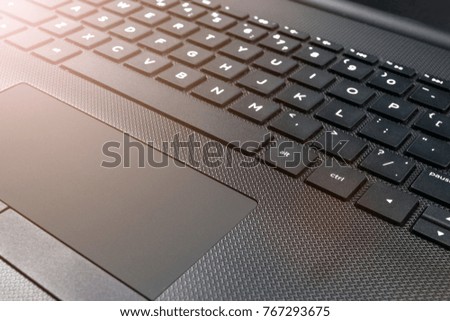 Close up view of a modern laptop computer keyboard keys and track pad. Soft lightning