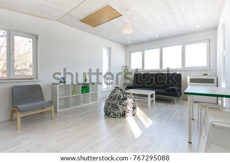 minimalistic living room interior, photo in cottage with wooden white celling, white painted walls, laminate floor. Royalty-Free Stock Photo #767295088
