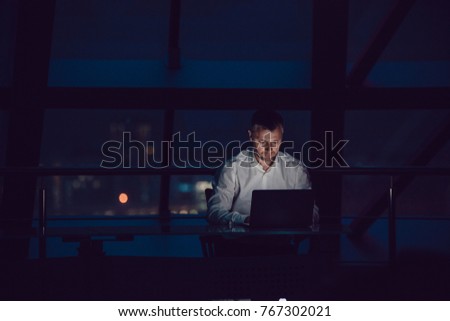 Businessman working on laptop in night office. Royalty-Free Stock Photo #767302021