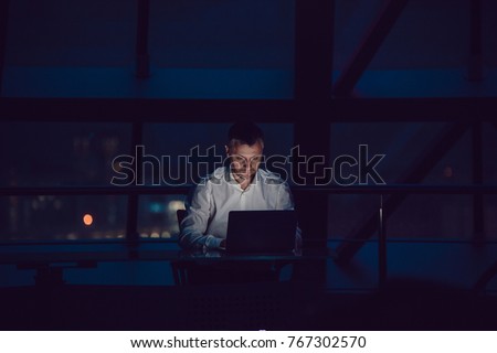 Businessman working on laptop in night office. Royalty-Free Stock Photo #767302570