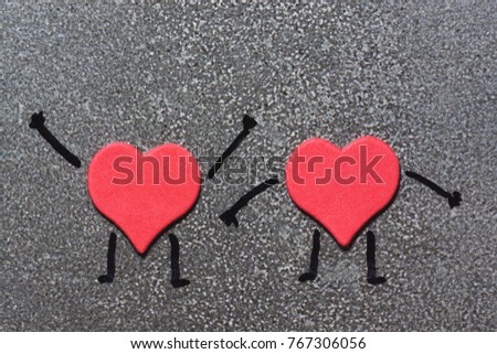 Two red hearts resembling a man with painted hands and feet on a gray background. Valentine's Day. Funny hearts