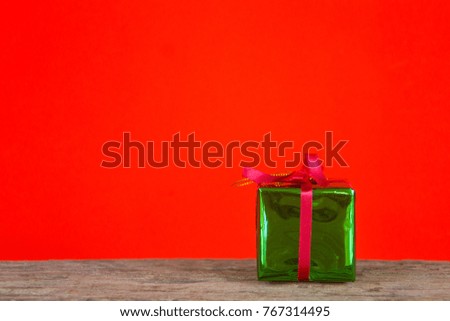 Green gift box on the wooden table with red background