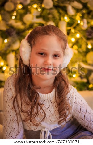 A little girl in the New Year's bedroom on the background of a Christmas tree and a garland