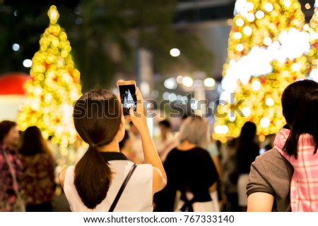 Woman hand holding mobile phone take a photo of christmas tree  and light