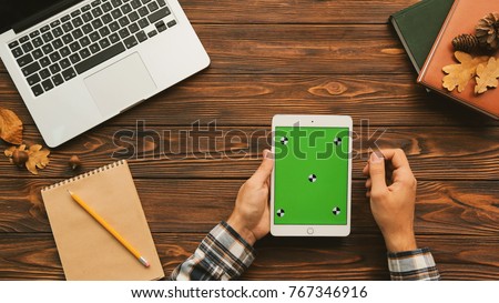 Top view of man using white tablet computer on the wooden table with laptop and notebooks. Tracking motion. Green screen. Chroma key.