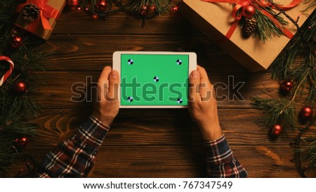 Christmas top view of man holding white tablet computer with green screen. Chroma key. Tracking motion. Christmas decor