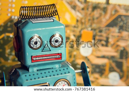Vintage tin toy robot with orange computer circuit board background, artificial intelligence concept