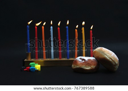 Hanukkah menorah with lighting candles, chocolate coins, dreidels and jelly doughnuts