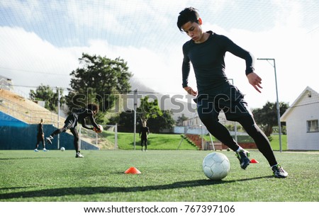 Football player training in soccer field. Young soccer player practicing ball control on training session. Royalty-Free Stock Photo #767397106