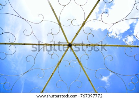 White wedding tracery openwork lattice against the blue sky, Artistic iron lattice against the blue sky.