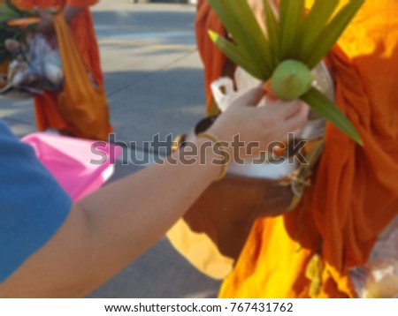 Making merit by giving food and flower to a monk in the morning. It's way of buddhism. It's blurred photo.