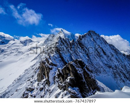 impressiv mountain landscape in the austrian alps with a massiv rock ridge  all covered with ice and snow on a perfect winter day, with a panoramic mountain skyline in the back