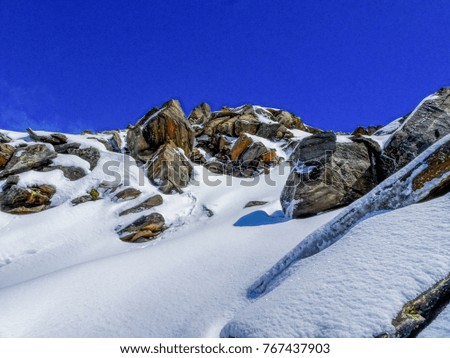 fresh fallen snow on granit rocks close to a austrian alps mountain peak on a blue sky day